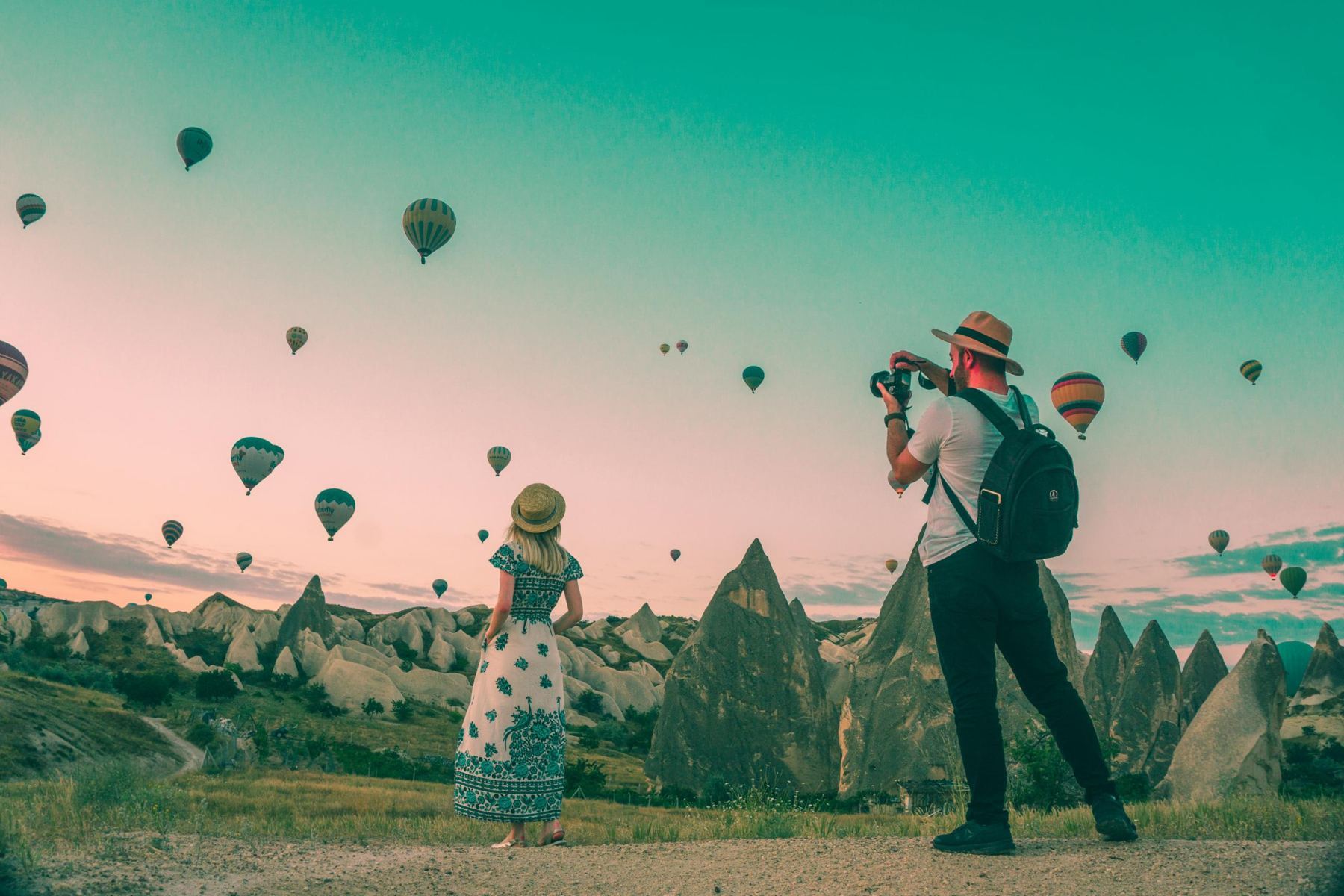 Travelers watching hot-air balloons at sunrise